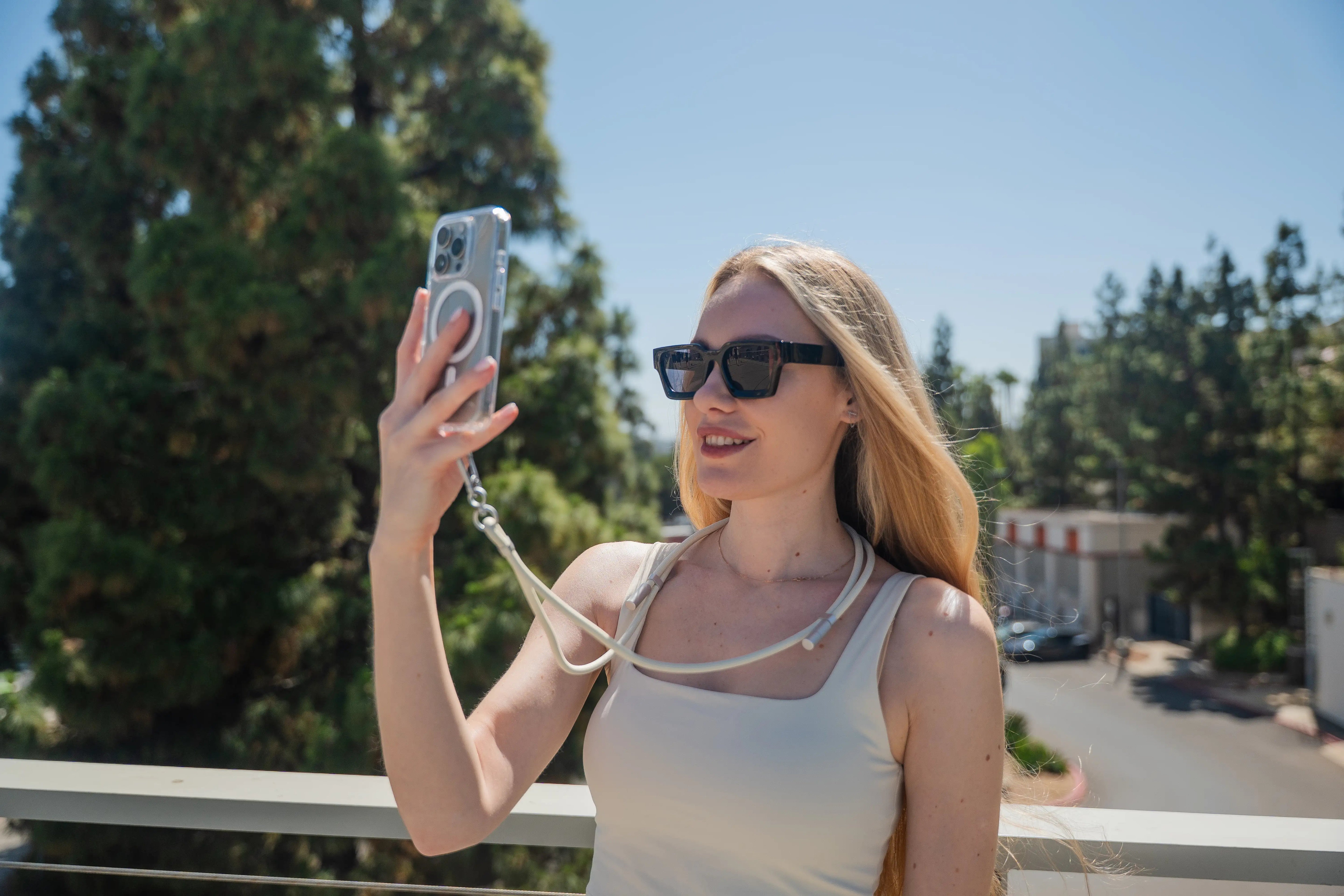 Woman holding an iPhone while attached to a Satechi OntheGo™ USB-C Lanyard Cable.