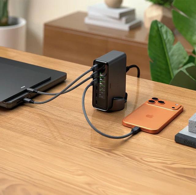 Satechi ChargeView™ 240W Desktop Charger with a small display showing output wattage per port, charging a tablet and an orange iPhone on a wooden desk.