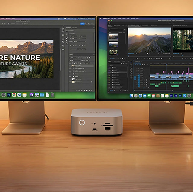 Satechi Thunderbolt 5 CubeDock™ with SSD Enclosure sitting between two monitors on a wooden desk, showing its front USB-C port, card slots and power button.