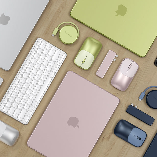 Satechi Slim EX Wireless Mouse, USB-C Snap Hub, and OntheGo™ 5-in-1 Multiport Adapter shown in four MacBook Neo colorways — Citrus, Indigo, Blush, and Silver — on a light wood desk. A blush MacBook, a citrus MacBook, and an indigo MacBook are arranged with color-matched accessories.