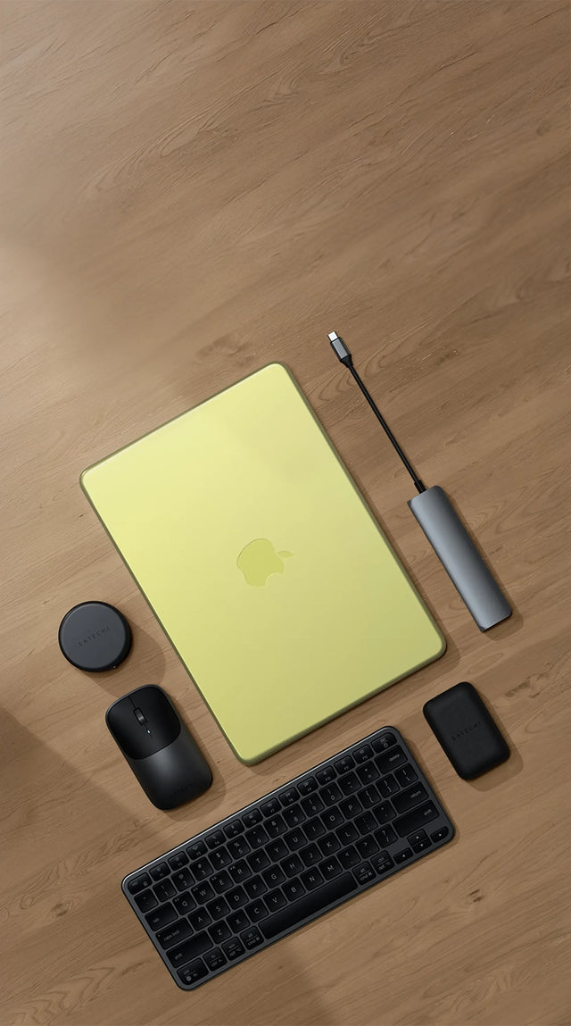 Top-down view of a Satechi workspace featuring a MacBook Neo on a light wood floor with a Satechi Slim EX1 Wireless Keyboard in dark, Slim EX Wireless Mouse, 7-in-1 USB-C Slim Multiport Adapter with Ethernet, and OntheGo™ 7-in-1 Multiport Adapter — best MacBook Neo accessories 2026