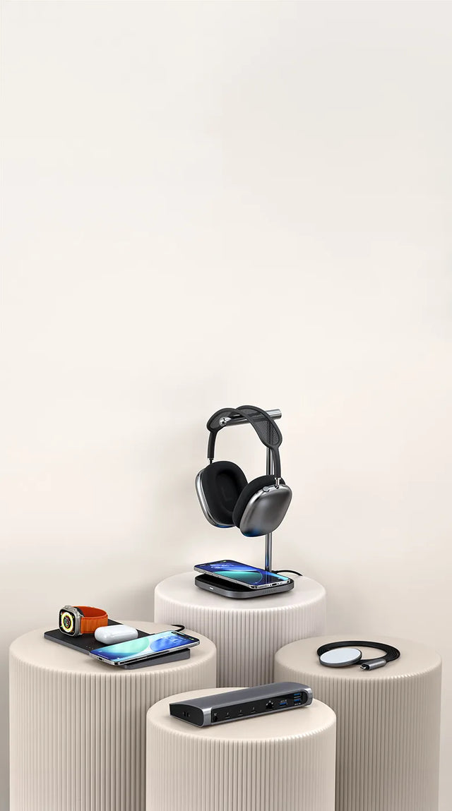 Satechi Trio Wireless Charger with Magnetic Pad, Thunderbolt 4 Dock, 2-in-1 Headphone Stand with Wireless Charger, and USB-C Magnetic Wireless Charging Cable displayed on neutral pedestal stands charging two iPhones, an Apple Watch, a pair of AirPods, and headphones. 