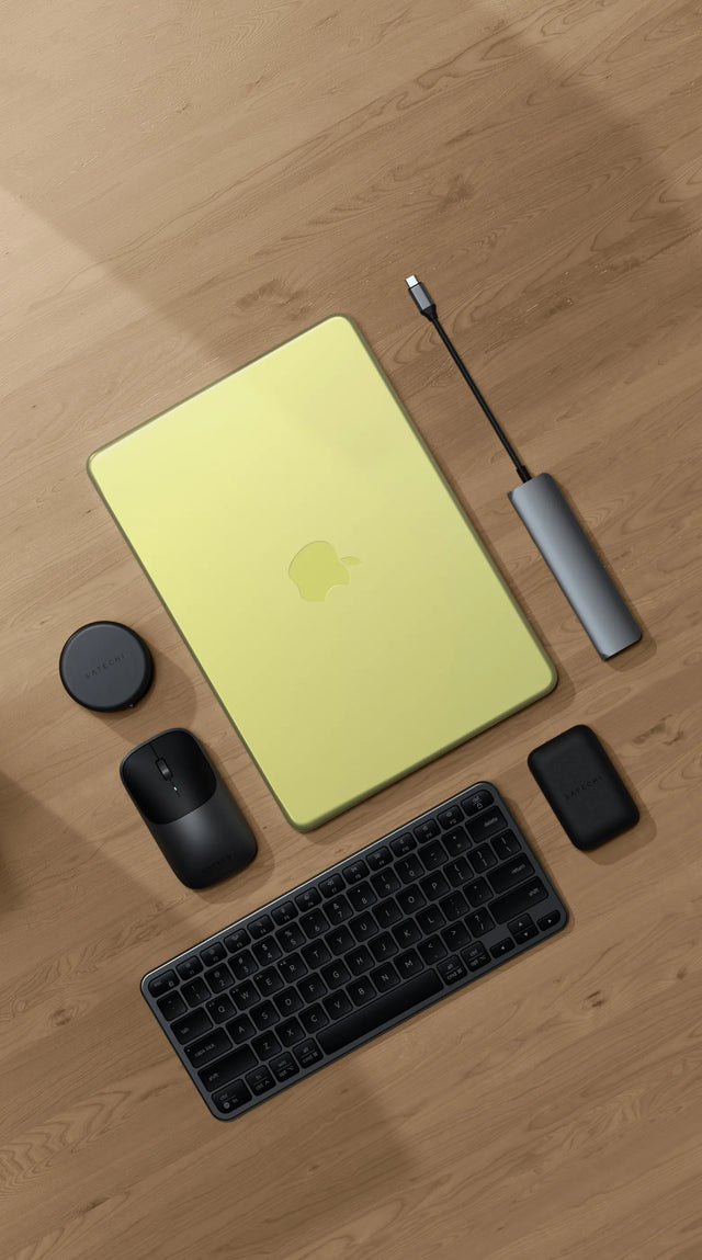 Top-down view of a Satechi workspace featuring a MacBook Neo on a light wood floor with a Satechi Slim EX1 Wireless Keyboard in dark, Slim EX Wireless Mouse, 7-in-1 USB-C Slim Multiport Adapter with Ethernet, and OntheGo™ 7-in-1 Multiport Adapter — best MacBook Neo accessories 2026