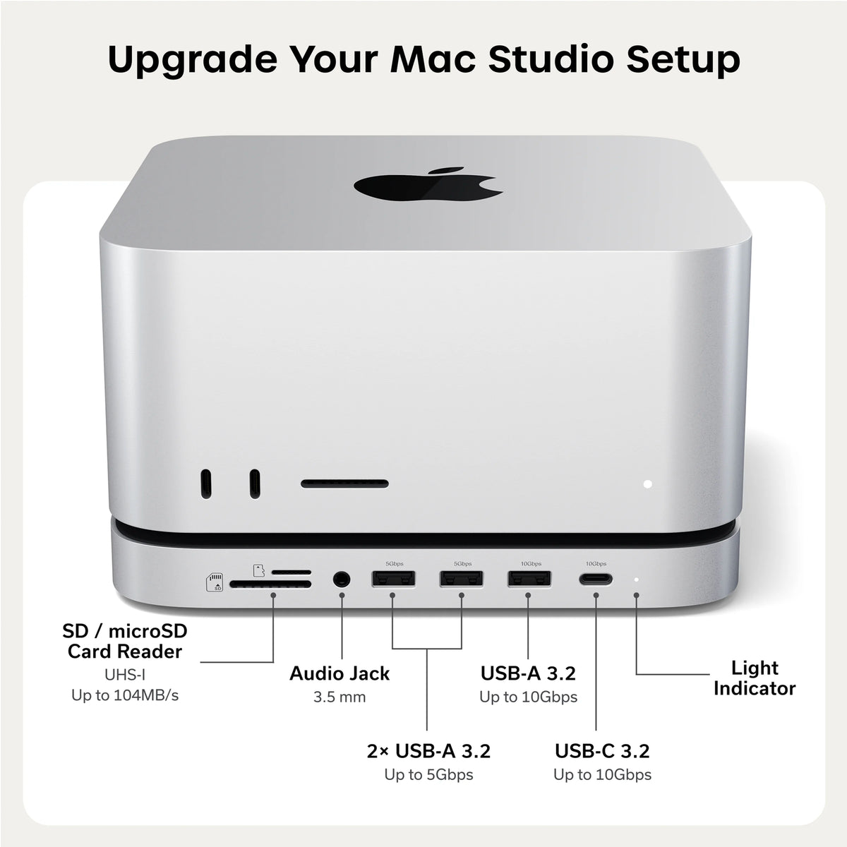 Upgrade Your Mac Studio Setup.” A silver Mac Studio sits on the Satechi Stand & Hub For Mac Studio M5 With NVMe SSD Enclosure. The matching aluminum stand works as a Mac Studio dock, with every front port labeled. From left to right: SD / microSD Card Reader, UHS-I, Up to 104MB/s. Audio Jack, 3.5 mm. 2× USB-A 3.2, Up to 5Gbps. USB-A 3.2, Up to 10Gbps. USB-C 3.2, Up to 10Gbps. Light Indicator. Small labels printed above the ports read “5Gbps,” “5Gbps,” “10Gbps,” and “10Gbps.