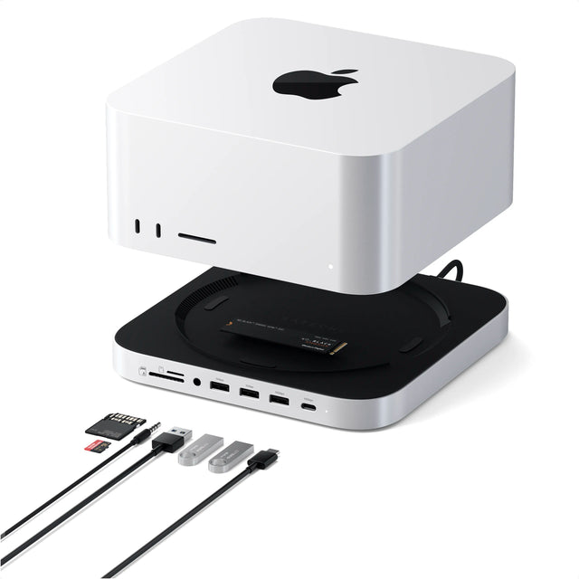 Satechi Stand & Hub For Mac Studio M5 With NVMe SSD Enclosure, a silver aluminum Mac Studio stand and hub, shown with a silver Mac Studio raised above it to reveal the stand’s black top panel with the Satechi logo. A WD_BLACK SN850X NVMe SSD from Western Digital sits in the built-in NVMe SSD enclosure. Its label reads “WD_BLACK™ SN850X NVMe™ SSD,”“WD_BLACK SN850X,” and “Western Digital.” Front ports from left to right: SD card reader, microSD card reader, 3.5mm audio jack, USB-A labeled “5Gb