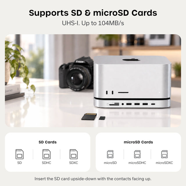 “Supports SD & microSD Cards. UHS-I. Up to 104MB/s.” A silver Mac Studio sits on the Satechi Stand & Hub For Mac Studio M5 With NVMe SSD Enclosure on a white desk, next to a camera, an SD card, and a microSD card. “SD Cards”: SD, SDHC, SDXC. “microSD Cards”: microSD, microSDHC, microSDXC. “Insert the SD card upside-down with the contacts facing up.”