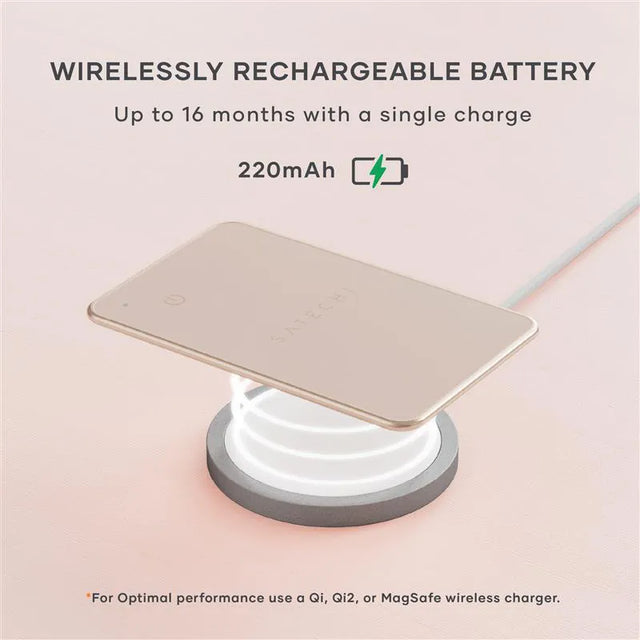 Satechi FindAll Card charging wirelessly on a Qi‑compatible charging pad, highlighting its long‑lasting rechargeable battery. A charging icon floats above. Text says " WIRELESSLY RECHARGEABLE BATTERY
Up to 16 months with a single charge
220mAh. *For Optimal performance use a Qi, Qi2, or MagSafe wireless charger."