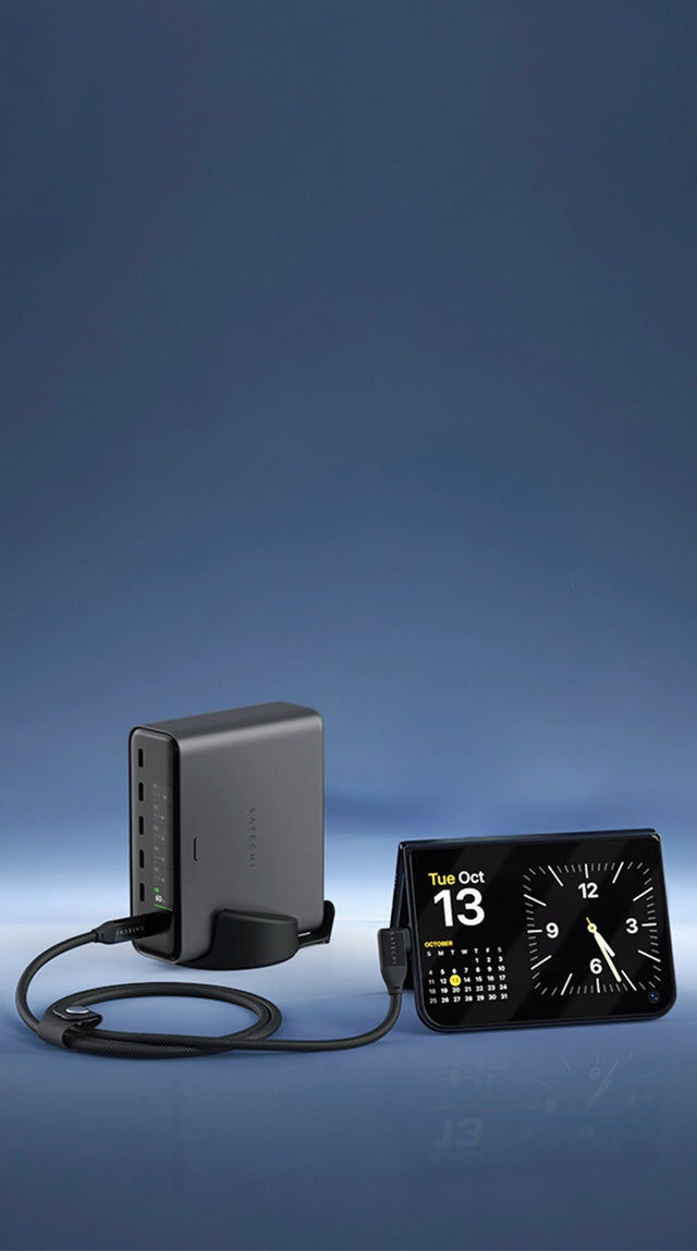 Desktop charging setup for iPhone Duo in a row from left to right: the Satechi ChargeView™ 240W Desktop Charger, an iPhone Duo folded into tent mode showing a clock and calendar for Tuesday, October 13 and connected with the Right-Angle USB-C to USB-C Data and Charge Cable (1m), 