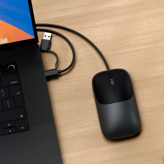 Slim LX Wired Mouse connected to a laptop on a wooden surface with its USB-C cable with integrated USB-C to A adapter.