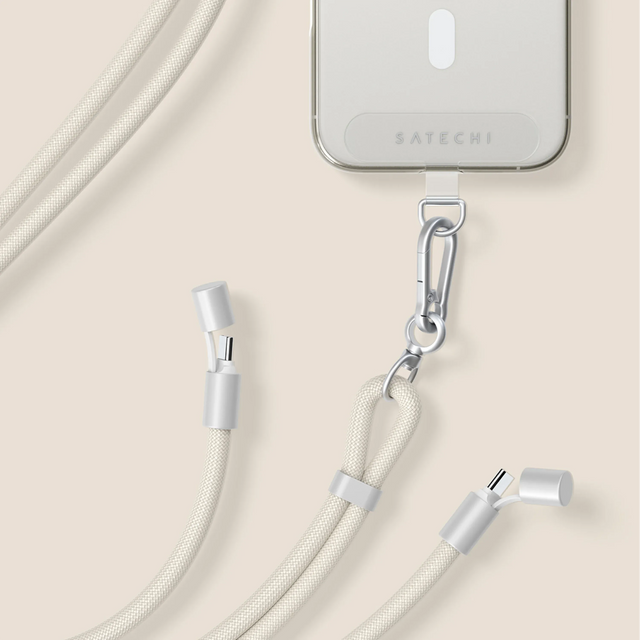 iPhone cu un cablu Satechi OntheGo™ USB-C Lanyard conectat la o husă transparentă pe un fundal bej.