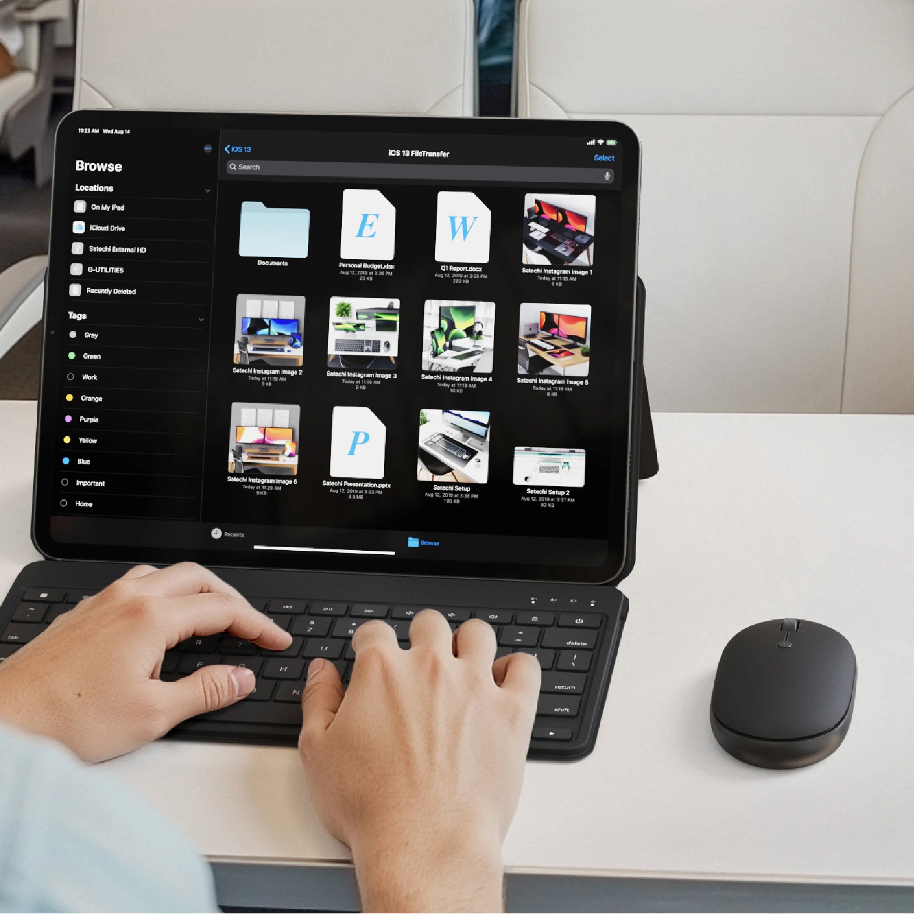 A person uses a black wireless keyboard and OntheGo™ Bluetooth Mouse in black with a tablet on a white desk. The tablet screen shows a web interface, and the person's hands are visible typing on the keyboard.