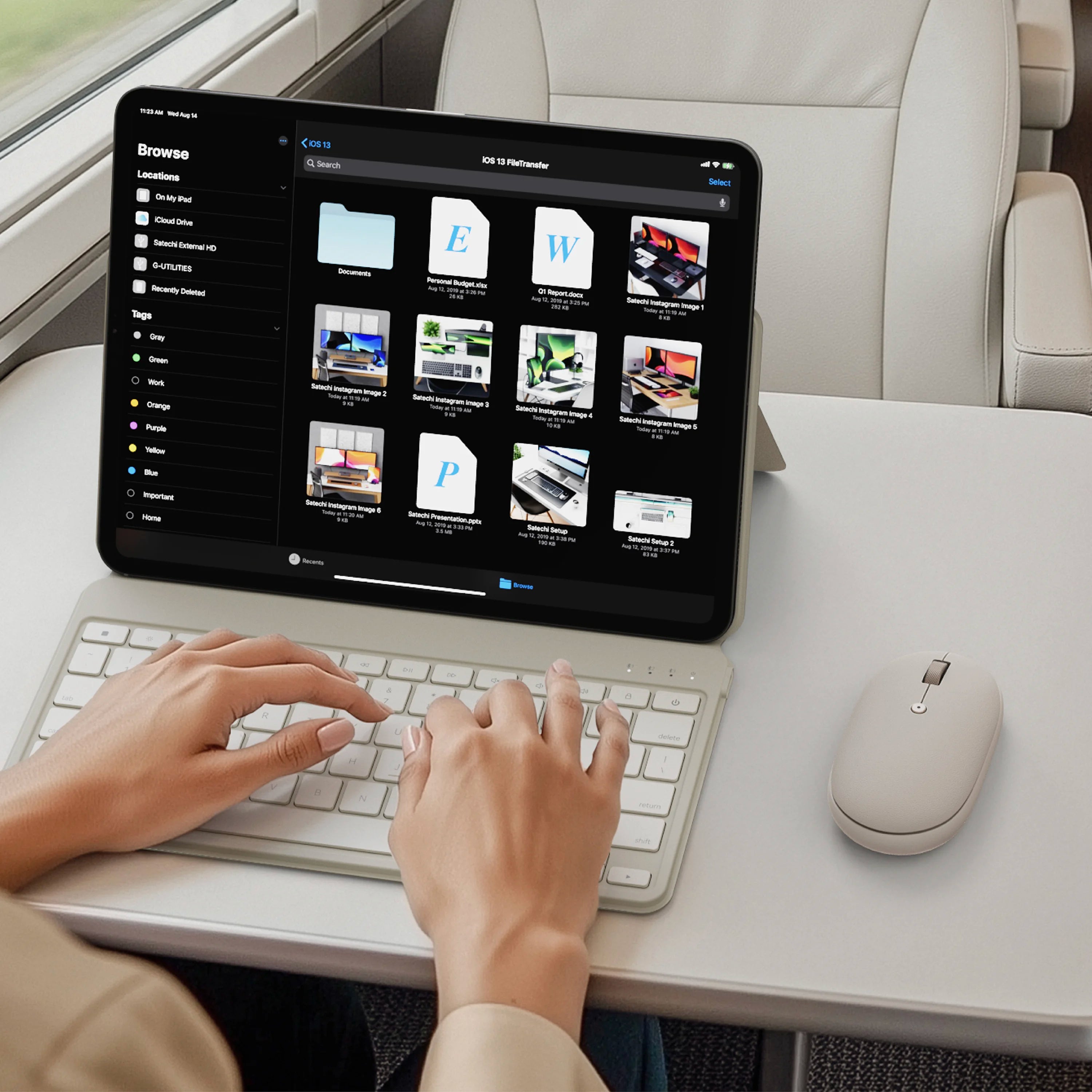 A person uses a sand wireless keyboard and OntheGo™ Bluetooth Mouse in sand with a tablet on a white desk. The tablet screen shows a web interface, and the person's hands are visible typing on the keyboard.