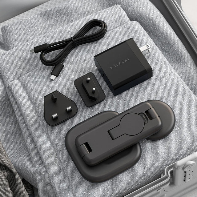 Satechi 3‑in‑1 Foldable Wireless Charging Stand with Qi2 25W, shown folded with USB‑C power adapter, charging cable, and interchangeable international plug attachments in a travel case.