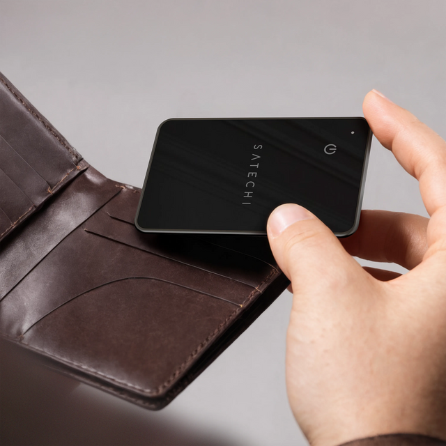 Person sliding the Satechi FindAll Card into a wallet slot, demonstrating its slim, card‑sized design.