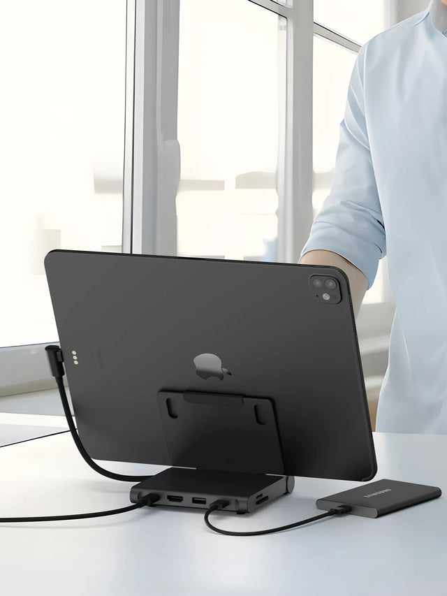 An iPad connected to the Satechi OntheGo™ Foldable Stand Hub on a desk, with the hub’s USB‑C and data ports in use. A camera, SD card, and external SSD sit nearby to show photo‑editing and file‑transfer workflow compatibility.