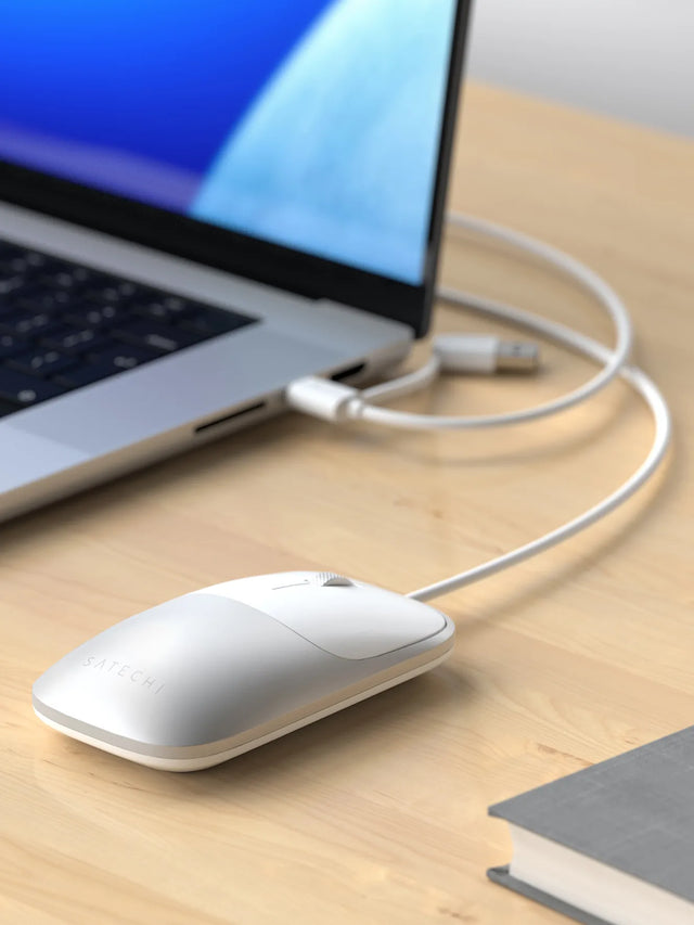 Slim LX Wired Mouse on a wooden desk with a laptop in the background.