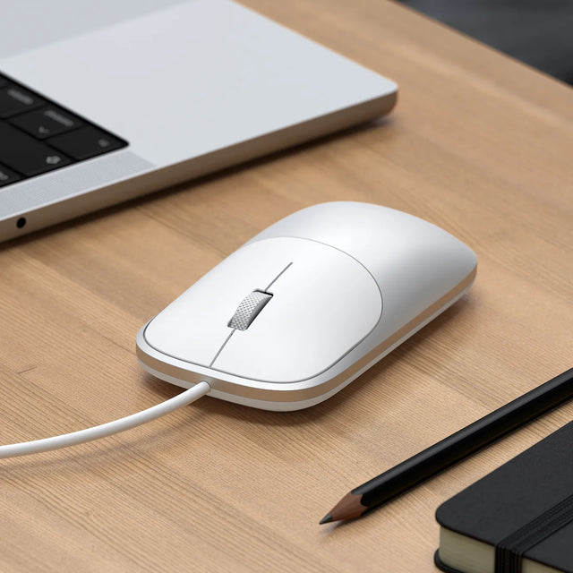 Slim LX Wired Mouse on a wooden desk with a laptop, pen, and notebook.