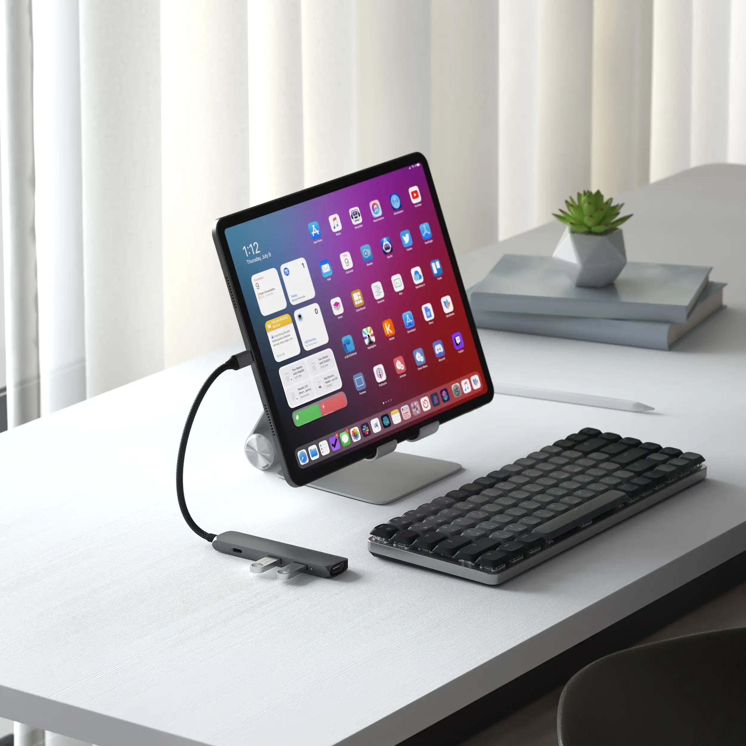 Satechi 4-in-1 USB-C Slim Multiport Adapter 4K connected to an iPad on a stand, positioned in front of the SM1 Slim Mechanical Backlit Bluetooth Keyboard, illustrating a compact and efficient desktop setup.