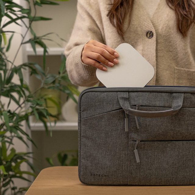 Satechi USB4 Slim NVMe SSD Enclosure being placed into a gray travel laptop bag, highlighting its compact, lightweight, and travel‑friendly design for portable high‑speed storage.